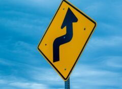 road sign turning arrow against blue sky with clouds