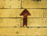 upward arrow on brown wooden panel