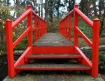 red wooden bridge leading to wooded area