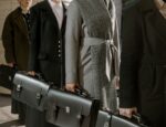 people waring coats in a line holding black briefcases