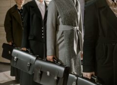 people waring coats in a line holding black briefcases
