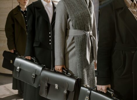 people waring coats in a line holding black briefcases